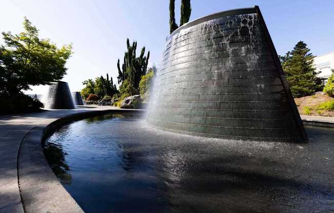 A water feature in a park with a tall, black, cylindrical structure at Spyglass Hill Apartments, Bremerton, 98337