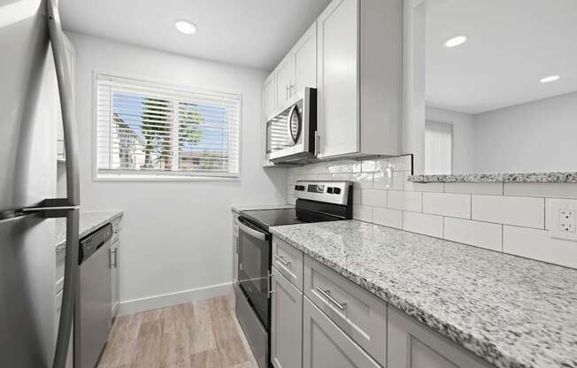 A kitchen with granite countertops and stainless steel appliances.