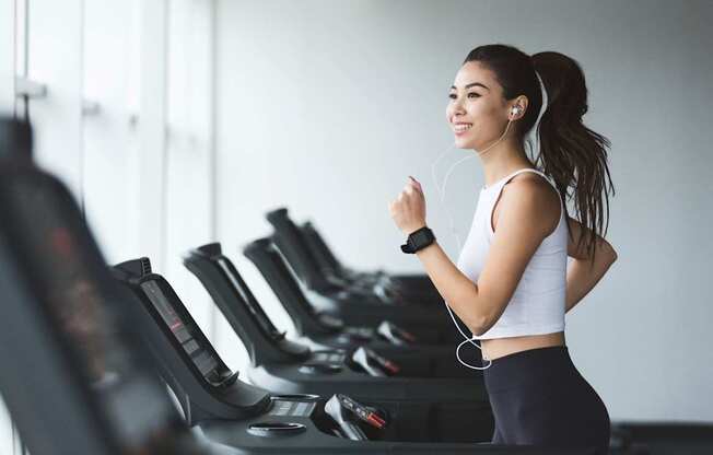 A woman is running on a treadmill in a gym.