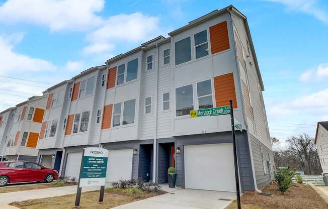 A multi-story apartment building with a sign in front that reads "Monarch Creek".