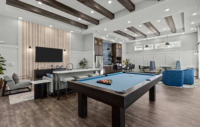 A pool table is in the middle of a room with a TV and a bar.