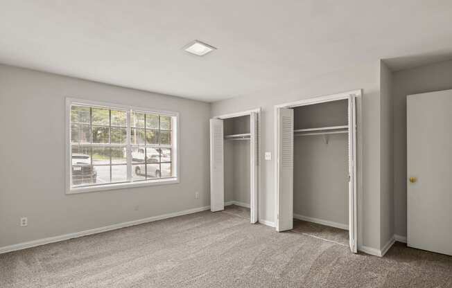 an empty bedroom with two closets and a window