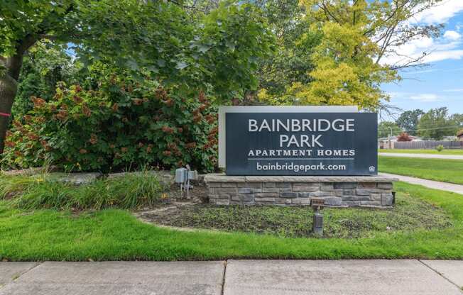 a sign in a grassy area with trees in the background