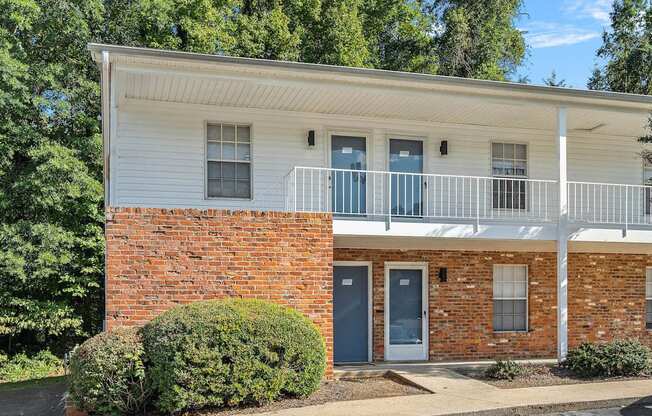 the front of a brick building with a porch and a balcony
