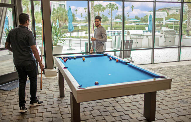 two men playing pool in the screened outdoor pavilion