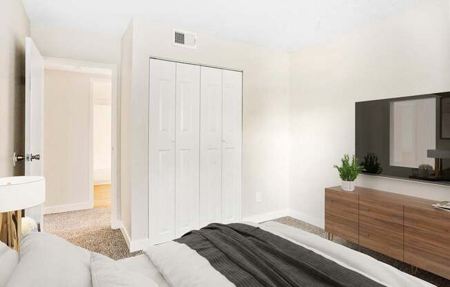 A white bedroom with a bed, dresser, and mirror.