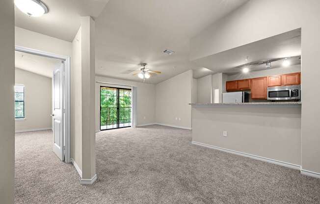 A spacious living room with a kitchenette in the background.