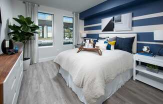 a bedroom with a large bed with white and blue bedding and a blue and white striped