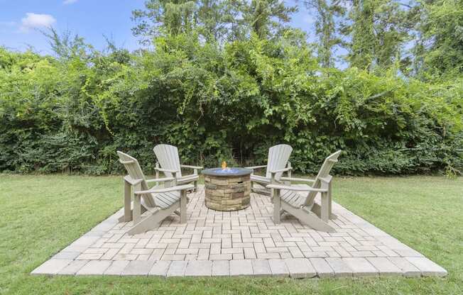 a backyard with a patio with chairs and a fire pit