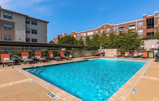A swimming pool surrounded by chairs and buildings.