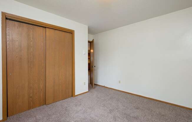a bedroom with a closet and a door to a hallway. Fargo, ND Gemstone Apartments