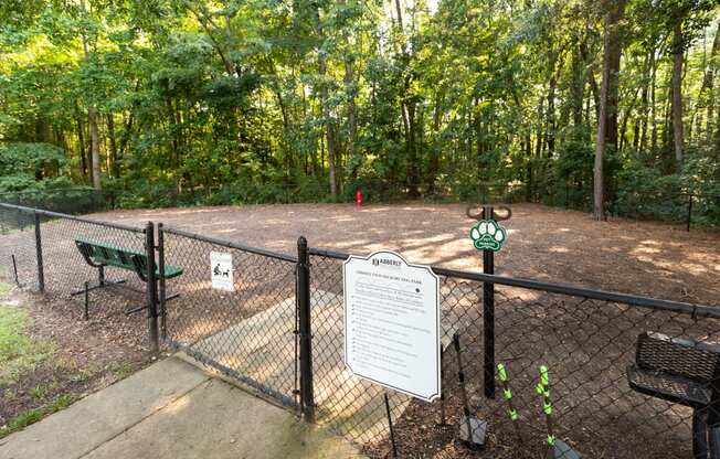 a dog park with a fenced in area and trees in the background