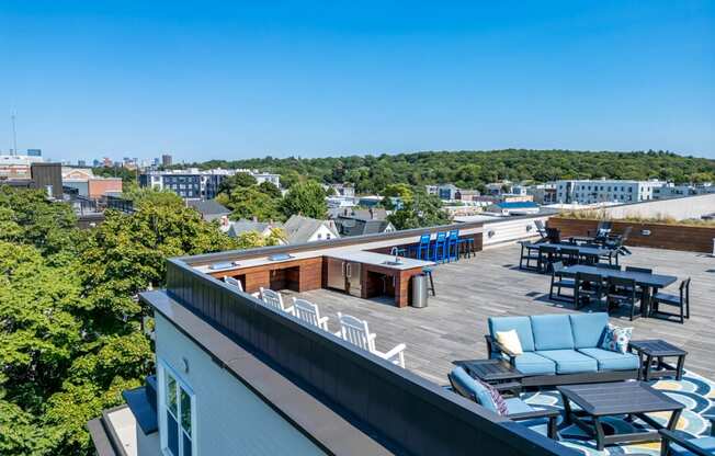 a rooftop deck with furniture and a view of the city