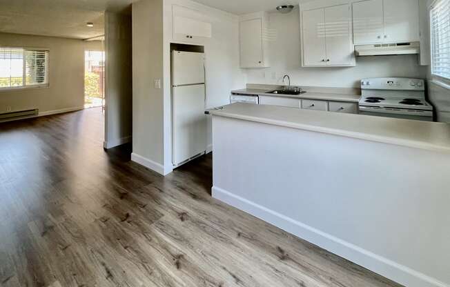 an empty kitchen with white cabinets and a white counter top