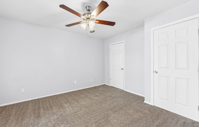 an empty living room with a ceiling fan