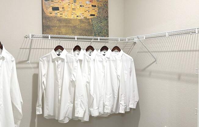 a closet with white clothes and a painting on the wall