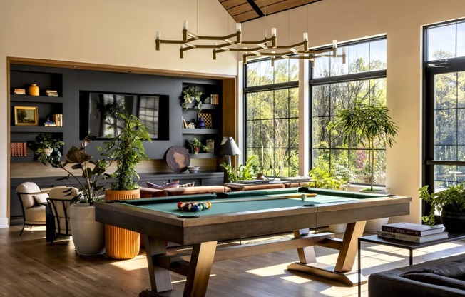 a pool table in a living room with large windows