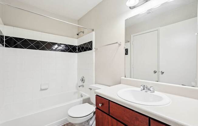 bathroom with brown cabinets and white sink and shower tub