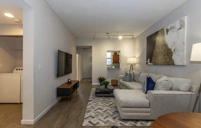 A living room with a grey couch and a television on the wall.