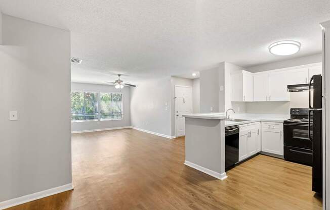 Model view of kitchen counter and living room  with wood flooring at Huntington Place in Sarasota, Florida.