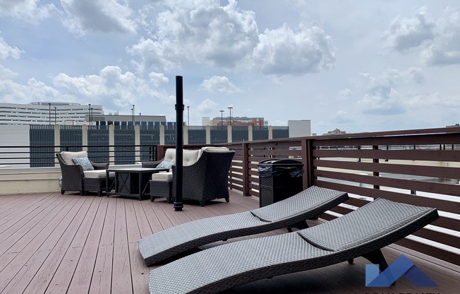 a roof top deck with lounge chairs and a fire pit