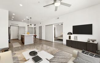 an open living room with a kitchen and a ceiling fan