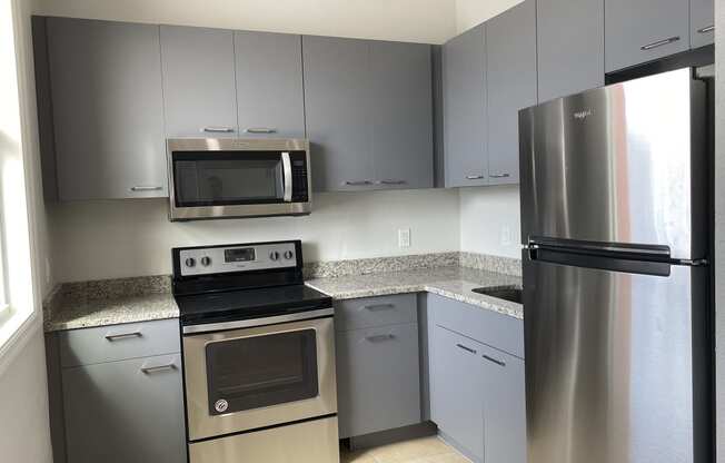 a kitchen with gray cabinets and stainless steel appliances at Colonial Apartments, Florida