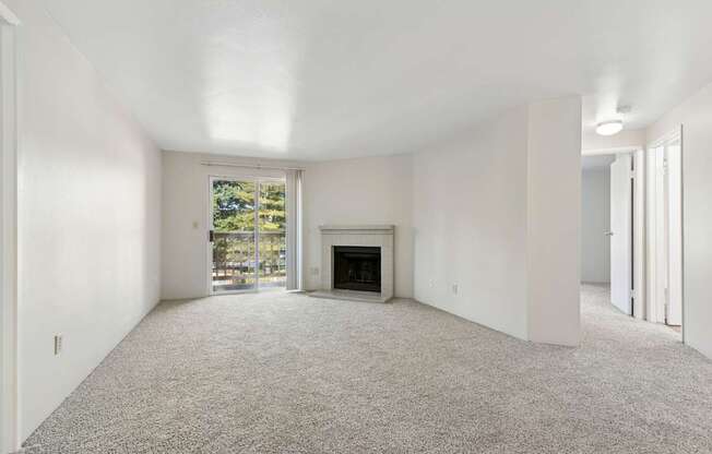 A spacious living room with a fireplace and a large window.