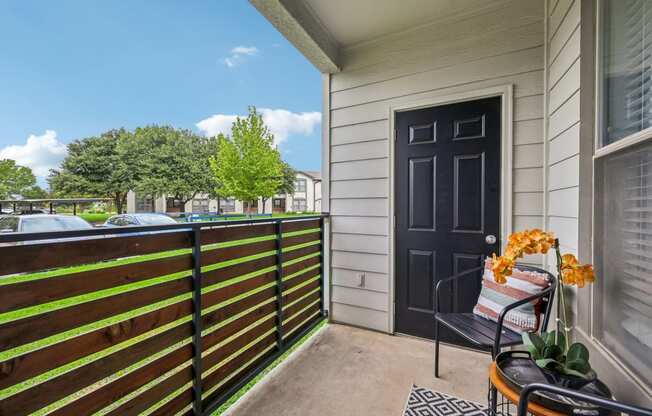 a balcony with a black door and a chair on it