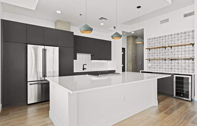 A modern kitchen with a white island and black cabinets.