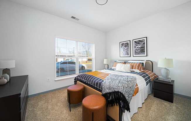 A bedroom with a bed, nightstand, and two stools.