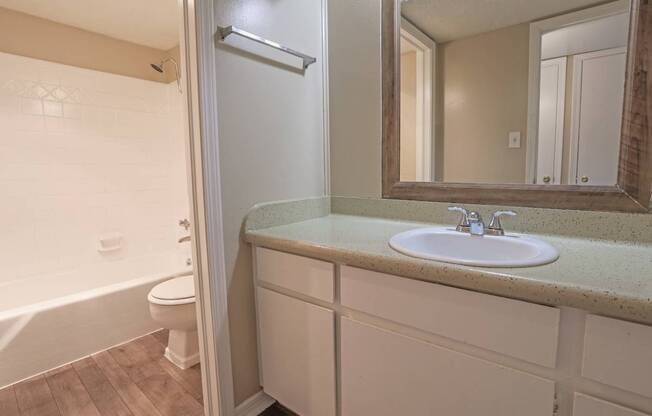 A bathroom with a sink, mirror, toilet, and bathtub at The Creole Apartments in Shreveport, LA