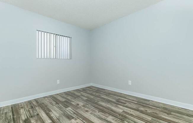 A room with a window and wooden flooring.