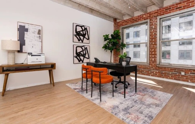 a living room with a table and chairs in front of a brick wall