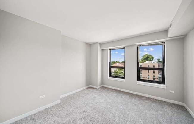 A room with a carpeted floor and a window showing a view of a building.