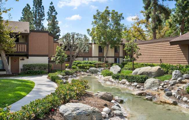 a pond in front of a building with trees and rocks