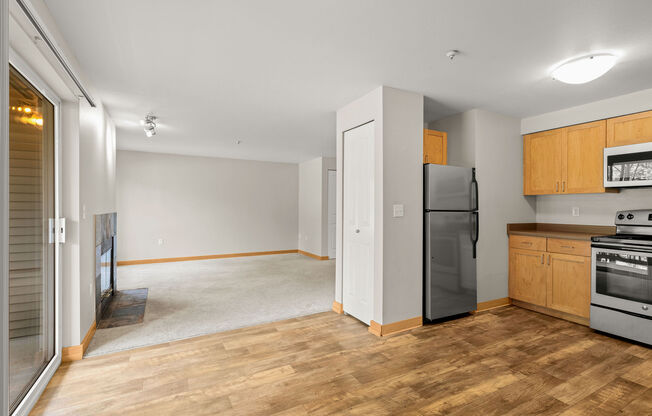A kitchen with wooden floors and a black fridge.
