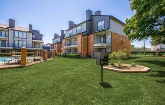 A grassy area in front of a building with a mailbox.