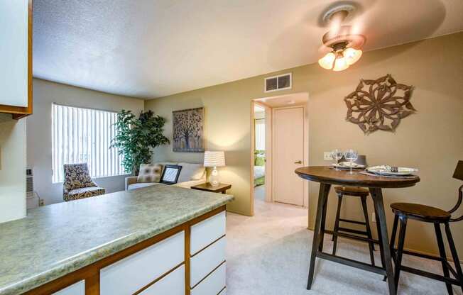 a kitchen with a bar and a living room with a table