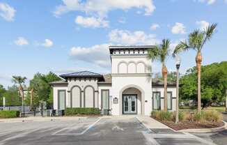 A white building with a black roof and palm trees in front.