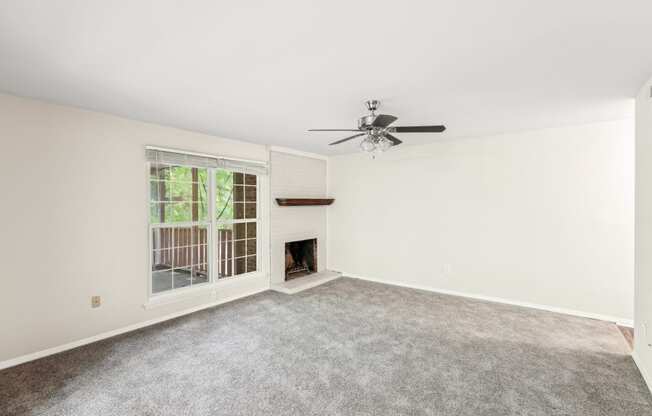 an empty living room with a fireplace and a ceiling fan