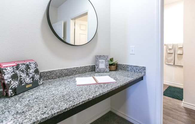 a bathroom with a granite countertop and a round mirror