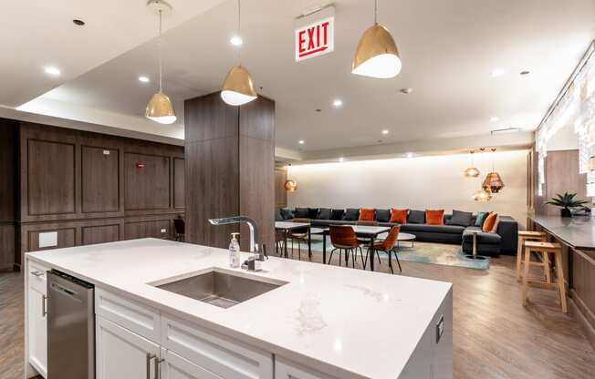 a kitchen with a sink and a counter top and a living room with couches