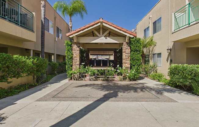 A patio area with a table and chairs surrounded by buildings and plants.