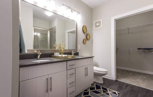 A bathroom with a sink, mirror, toilet, and a shower.