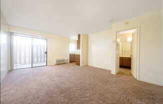 a bedroom with a large window and a door leading to a kitchen at Park Columbia Apts, Hemet, 92544