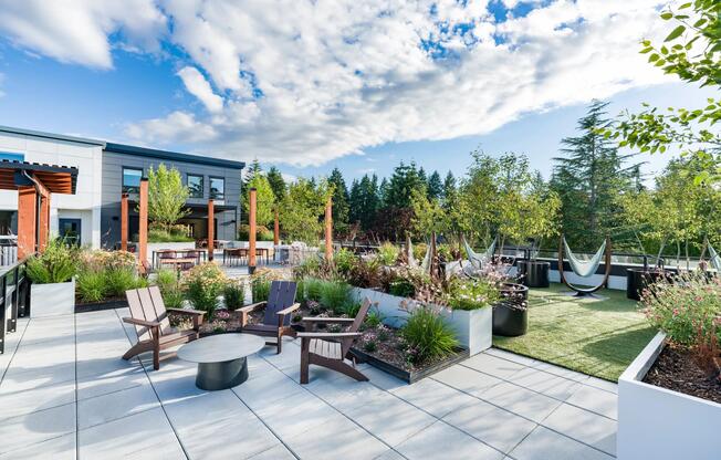 The rooftop terrace features landscaped gathering spaces, lounge seating, hammock-style retreats, and outdoor social areas designed to connect residents with the natural beauty of the Pacific Northwest.