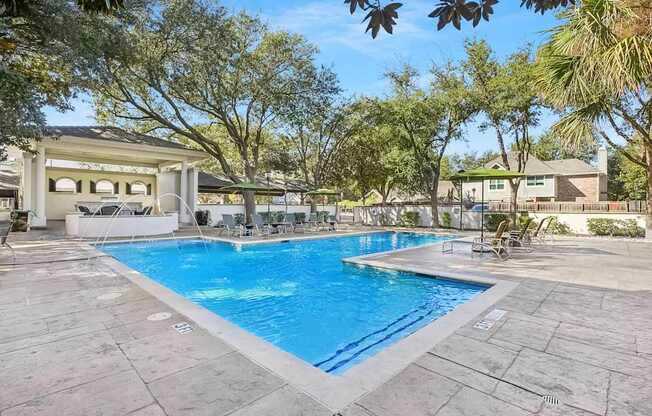 A large swimming pool surrounded by trees and a building in the background.