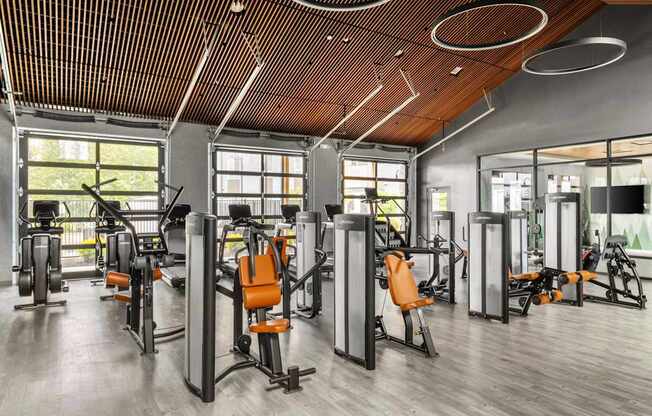 A gym with orange chairs and a wooden ceiling.