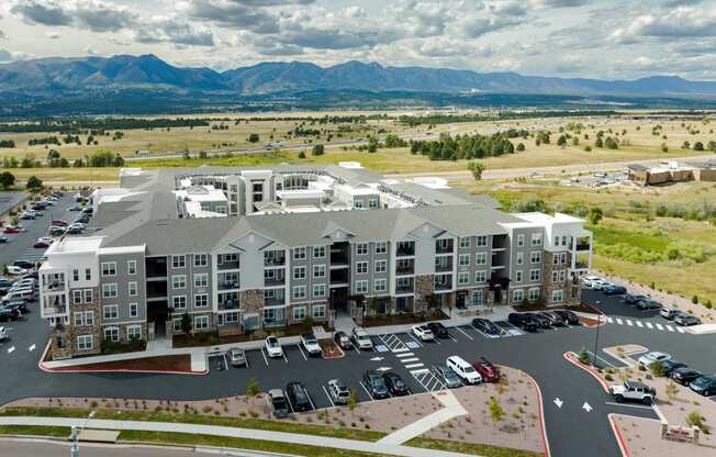 an aerial view of the zeb apartment complex with a parking lot and mountains in the background